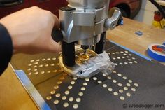 a person using a machine to cut holes in the metal sheet on top of a table