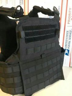 a black vest sitting on top of a table next to a bookcase with books behind it