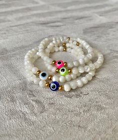 💕Evil Eye Bracelets, handcrafted from stunning 100% natural mother of pearl shell and high quality gold tarnish resistant beads💕 The evil eye is a protective and powerful symbol, also known as the Nazar. The evil eye helps to absorb negative energies, protect and bring luck. The evil eye makes a perfect gift for yourself and loved ones.  ✨All bracelets are lovingly handmade by me using high quality materials✨ Hand of Fatima Necklace https://www.etsy.com/uk/listing/1556603231/hamsa-hand-of-fatima-gold-pendant?click_key=a6f5da90d8d8ea8bd774c20becf761f1cd89bc53%3A1556603231&click_sum=a9a084e9&ref=shop_home_active_3 Hand of Fatima Earrings https://www.etsy.com/uk/listing/1542499652/hamsa-hand-of-fatima-gold-stud-earrings?click_key=89cabcb8ef68040716616f6d3e33732975d65ab1%3A1542499652&click_s Mother Of Pearl Bracelets With Round Beads As Gift, Mother Of Pearl Bracelets With Round Beads For Gift, Handmade Mother Of Pearl Bracelets With Round Beads, Mother Of Pearl Beaded Bracelets Gift, Mother Of Pearl Beaded Bracelets For Gifts, Mother Of Pearl Beaded Bracelet As A Gift, Mother Of Pearl Bracelets For Gifts, Adjustable Mother Of Pearl Bracelet, White Mother Of Pearl Beaded Bracelet As Gift