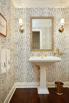 a white pedestal sink sitting under a mirror in a bathroom next to a wooden floor