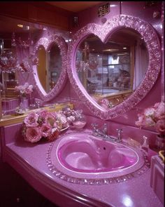 a pink bathroom with two heart shaped mirrors above the sink and flowers on the counter