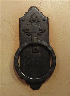 an old black door handle on a wall with a ring in the middle and a flower design at the center