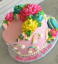 a pink birthday cake with flowers on it