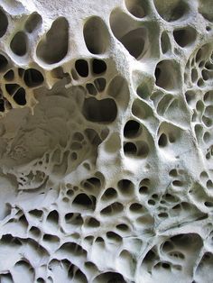 an artistic rock formation with holes in it