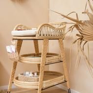 a wicker baby changing table next to a palm tree in the corner of a room