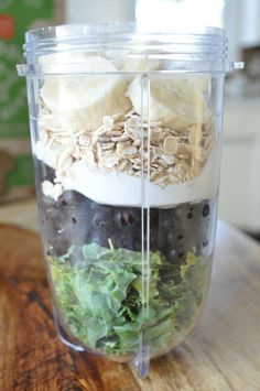 a blender filled with fruits and vegetables on top of a wooden table