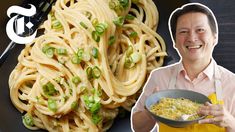 a man holding a bowl of noodles with peas on it and a fork next to him