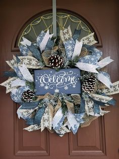 a welcome wreath with pine cones and ribbons hanging on the front door to give it a wintery feel