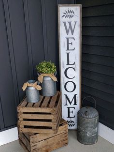 a welcome sign sitting on top of two wooden crates next to a potted plant