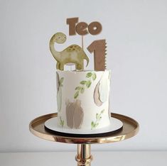 a dinosaur themed birthday cake with the number one on top and an icing decoration