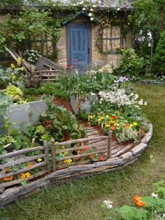 the garden is full of flowers and plants, including an old wooden fence with a blue door