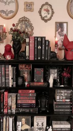 a book shelf filled with lots of books next to two framed pictures on the wall