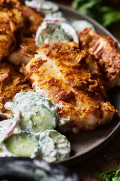 a plate with chicken, potato salad and cucumber