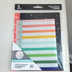 three different colored notebooks on top of a white table with space in the background