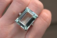 1920's cocktail ring with emerald cut aquamarine stone. 18.43 Carat aquamarine with six 0.18 carat diamonds on a 14kt white gold band. Aquamarine clarity A-AA and is 19.7mm x 15.2mm. Metal weight is 10.0g. Appraised value is $10,940 as of 08/09/2022. Appraisal paperwork available upon request. Please feel free to reach out with any questions! Formal Emerald Cut Aquamarine Diamond Ring, Formal Emerald-cut Aquamarine Diamond Ring, Aquamarine Cocktail Ring, Ring With Emerald, Swarovski Ring, Lapis Ring, Aquamarine Engagement Ring, Gold Statement Ring, Sterling Silver Marcasite