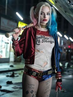 a woman dressed up as harley and holding a baseball bat in her right hand while standing on the street