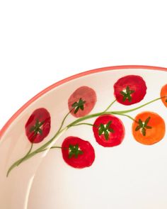 a white plate with red and orange tomatoes painted on the side, sitting in front of a white background