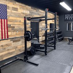 an empty gym with wooden walls and black barbells on the floor in front of it