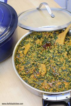 a pan filled with food sitting on top of a stove next to a blue pot