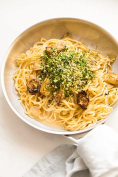 a plate of pasta with mushrooms and parmesan cheese on the side next to a napkin