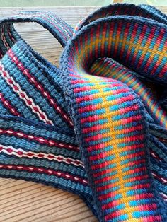 multicolored knitted scarf laying on top of a wooden table