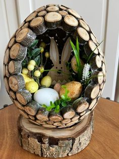 an easter decoration made out of logs and eggs in a basket on top of a wooden table