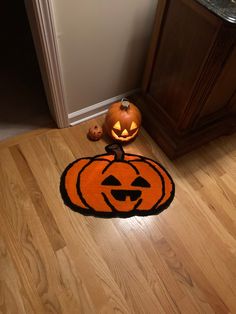 two pumpkins sitting on the floor in front of a cabinet and door with carved faces