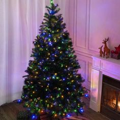 a lit christmas tree in front of a fireplace