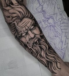 a man's arm with a black and grey tattoo on it