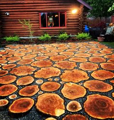 an outdoor area with wood slices on the ground in front of a log cabin at night