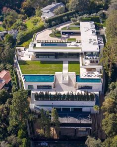 an aerial view of a house with a swimming pool in the center and trees surrounding it