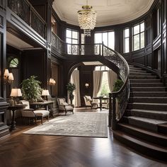 a large foyer with wooden floors and chandelier above the grand staircase that leads to another room