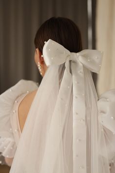 the back of a woman's wedding dress with a white bow on her head