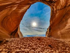 the sun is shining through an arch in the desert