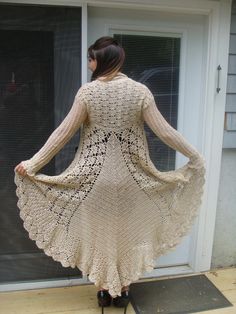 a woman is standing on a porch wearing a crocheted cardigan and black boots