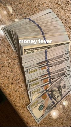 stacks of money sitting on top of a counter with the words money fever written above them