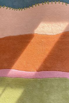 a multicolored area rug on the floor in front of a window with sunlight streaming through it