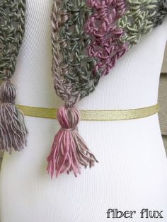 a white mannequin wearing a gray and pink scarf with tassels on it