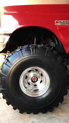 a red truck with large tires parked in a garage