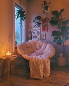 a living room filled with lots of plants next to a window and a chair in the corner