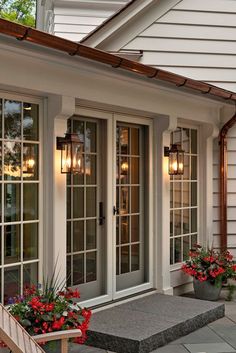 two potted flowers are sitting on the steps in front of a house with double doors