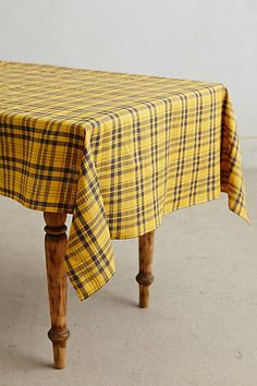 a yellow and black checkered table cloth on a wooden bench with legs in the foreground