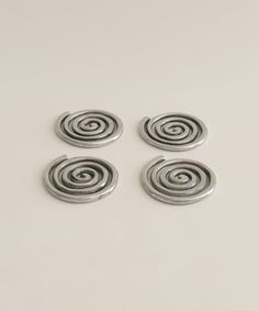 four silver spiral buttons on a white surface