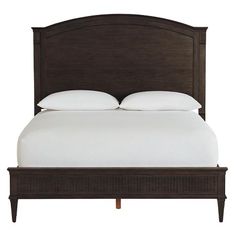 a bed with white pillows and brown headboard