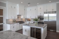 a large kitchen with white cabinets and marble counter tops, along with stainless steel appliances