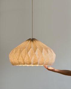 a person is reaching for a light hanging from a ceiling fixture that has geometric shapes on it