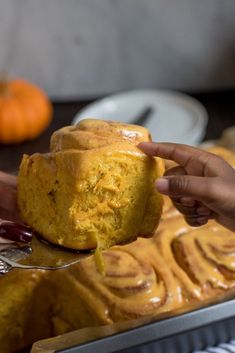 a person holding a bundt cake in front of some pumpkins on the table