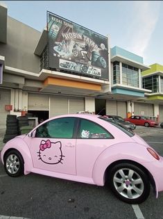 a pink car with hello kitty decals on the side parked in front of a building