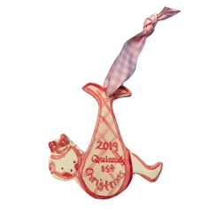 a ceramic ornament with a baby's first christmas design on it and a pink ribbon around the neck