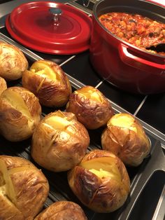 several baked goods sitting on top of a stove next to a red pot and pan